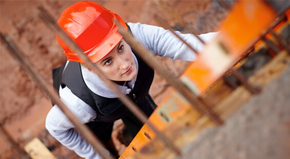young construction worker in an orange hardhat climbing up a ladder